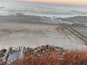 Rock "armoring" of beach bluffs with large tire tracks in the background